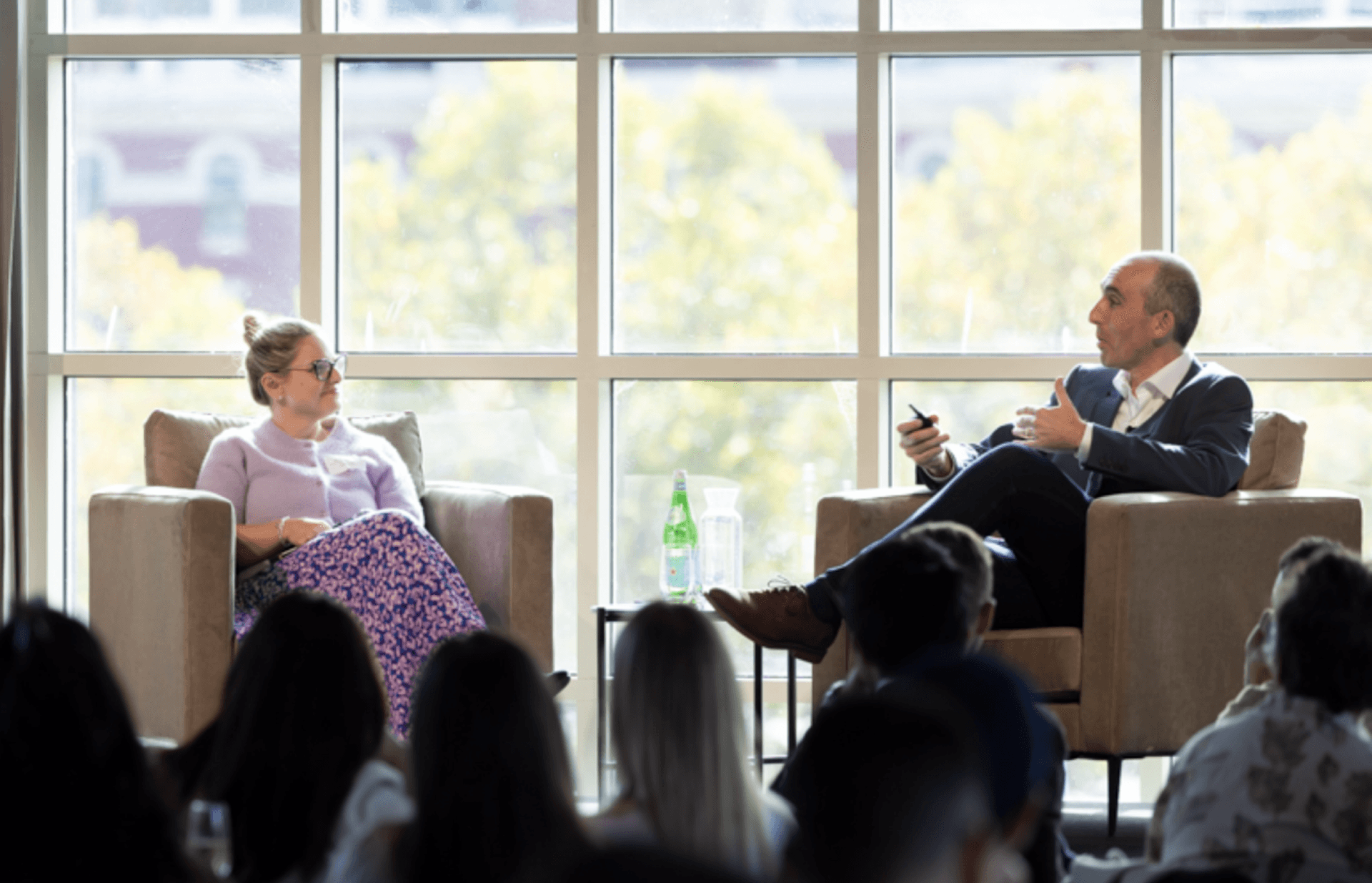 a man and a woman are sitting in front of a large window