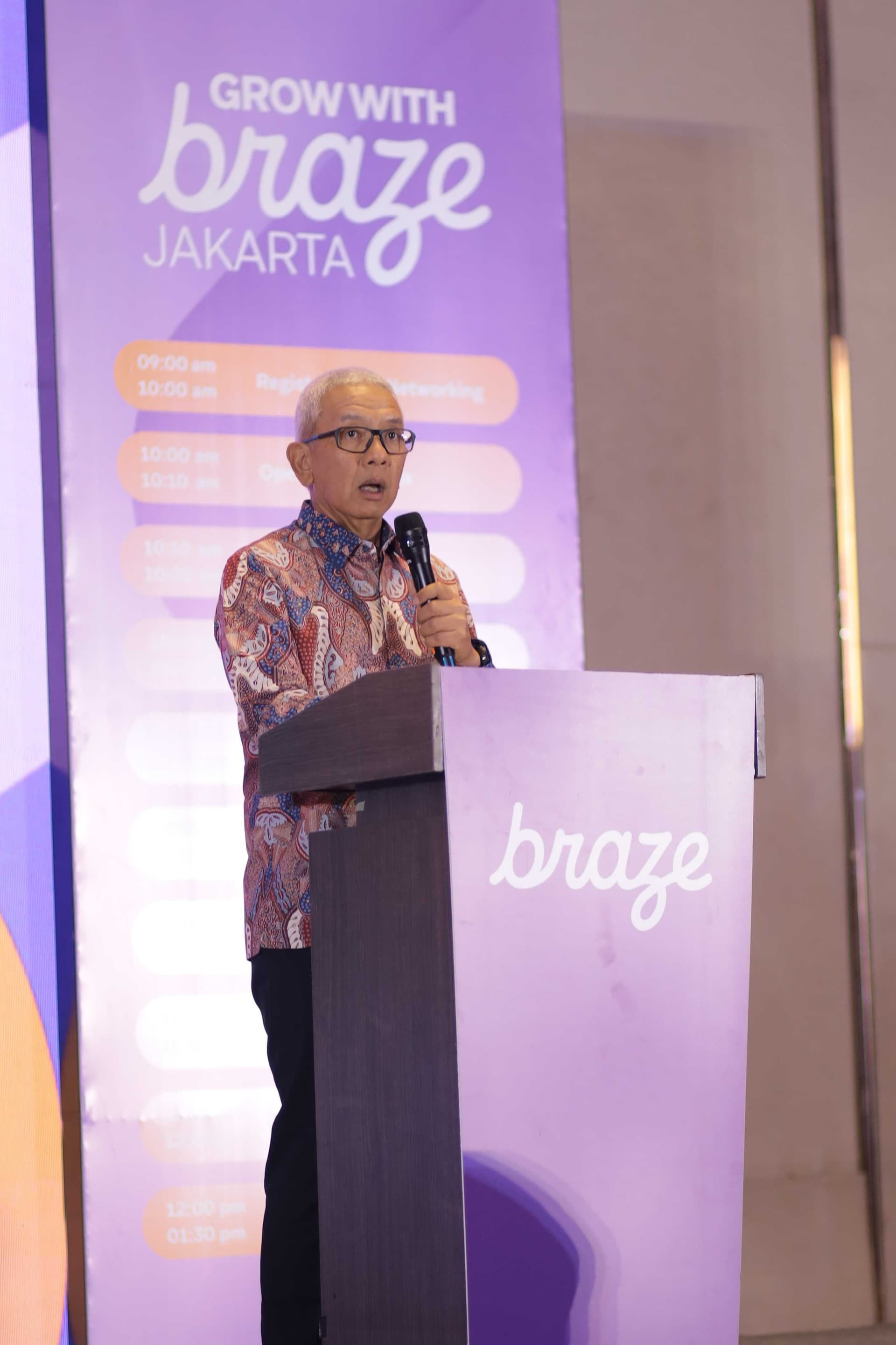 a man stands at a podium in front of a sign that says grow with braze jakarta