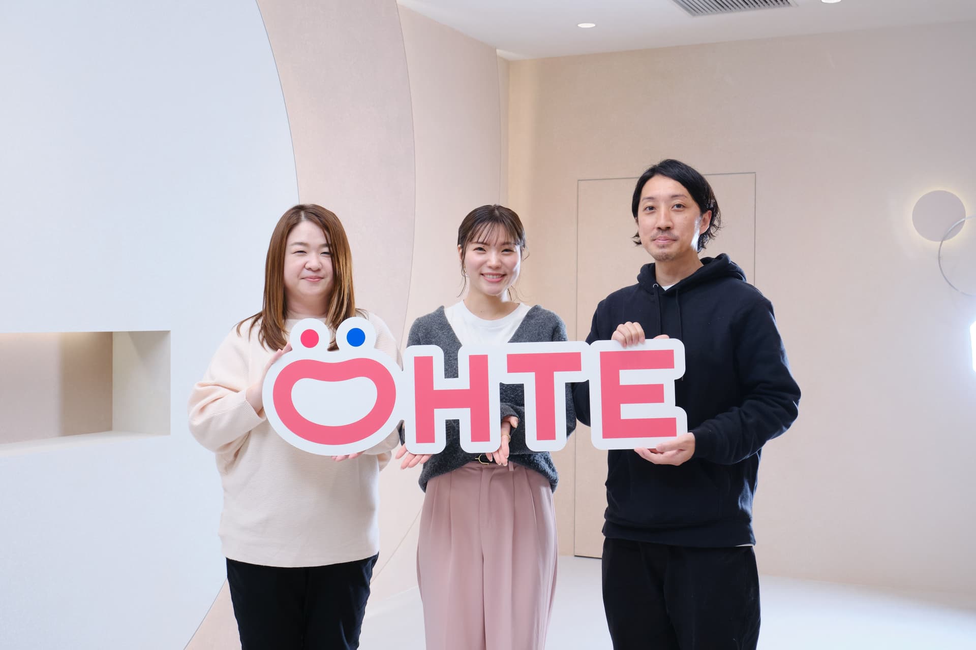 three people are standing next to each other holding a sign that says ohte .