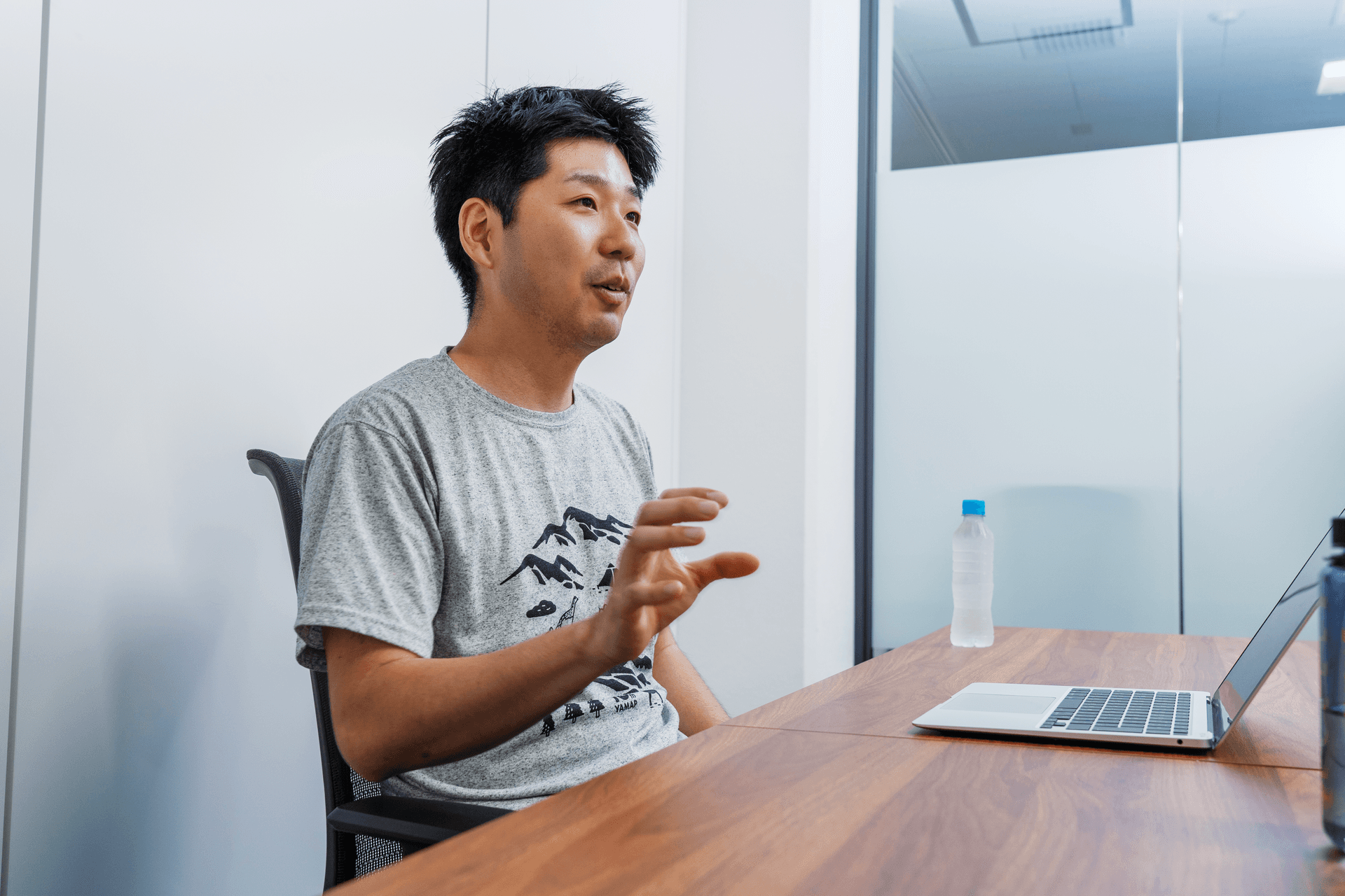 a man sitting at a desk with a laptop and a bottle of water