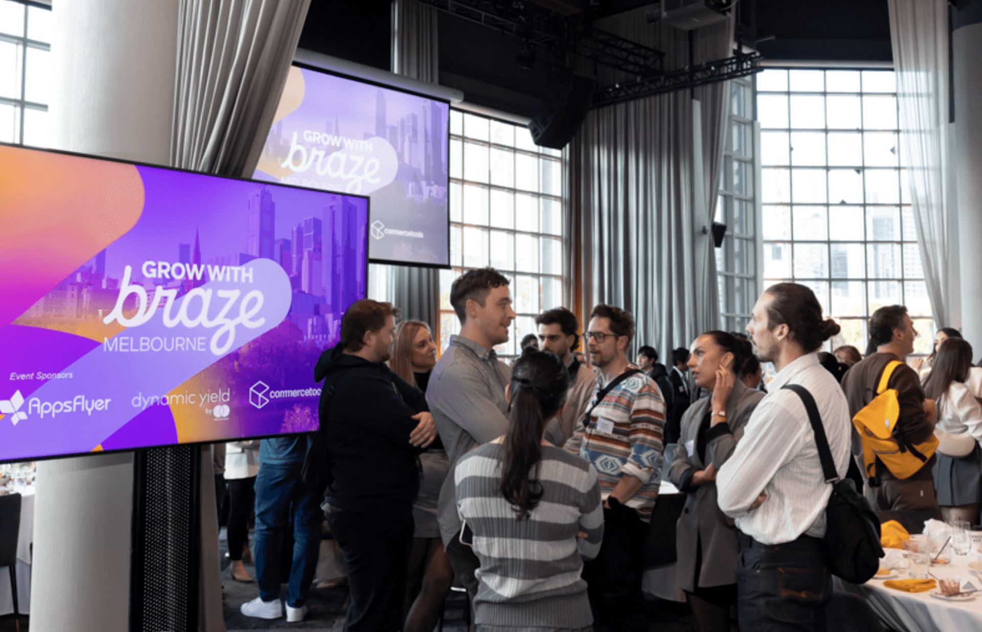 a group of people standing in front of a screen that says grow with braze