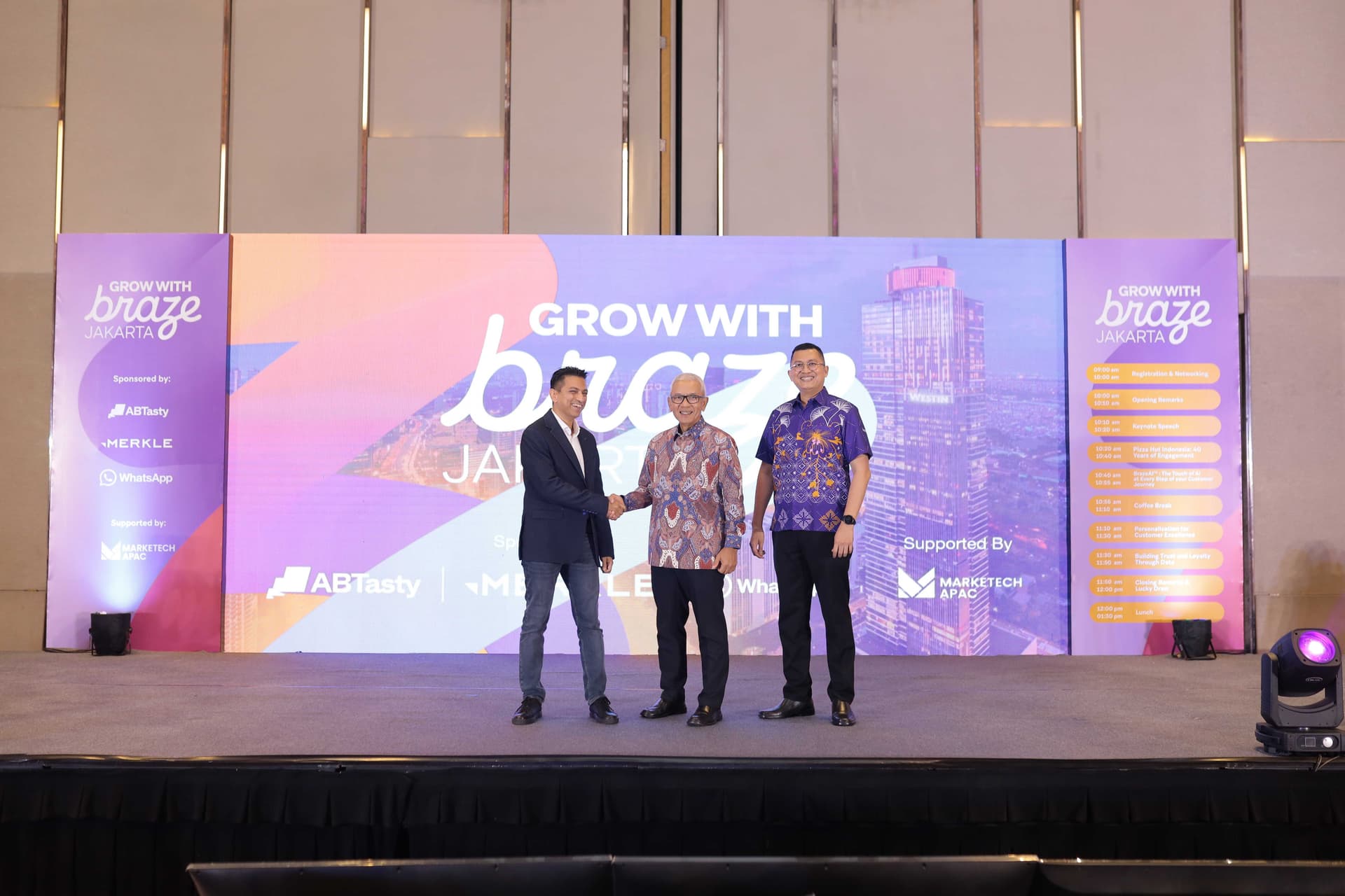 three men are standing on a stage shaking hands .