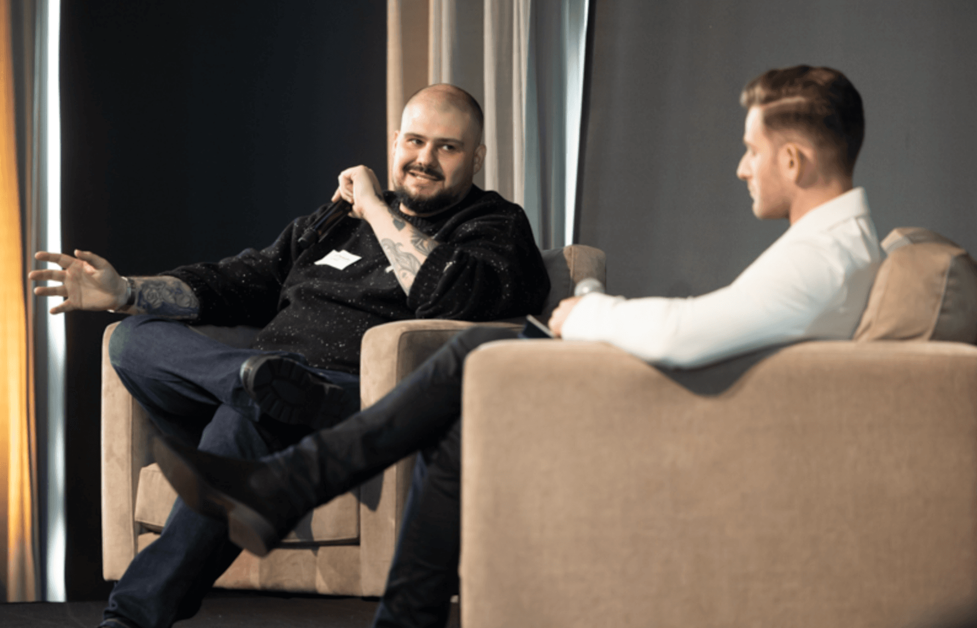 a man with a name tag on his shirt sits next to another man