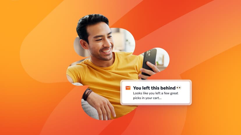 A smiling man looking at his phone, receiving a notification about items left in his shopping cart.