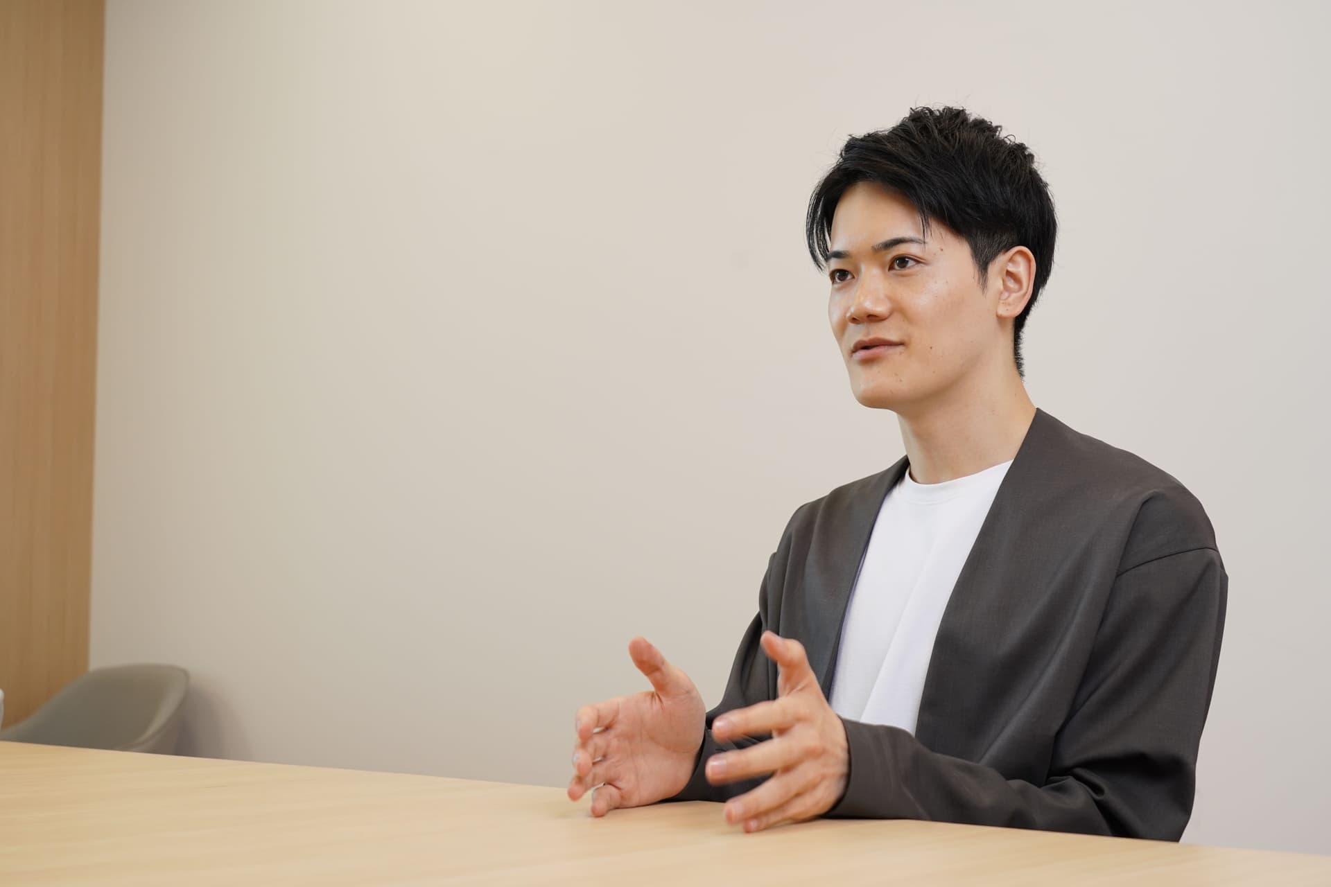 a young man is sitting at a table with his hands outstretched .