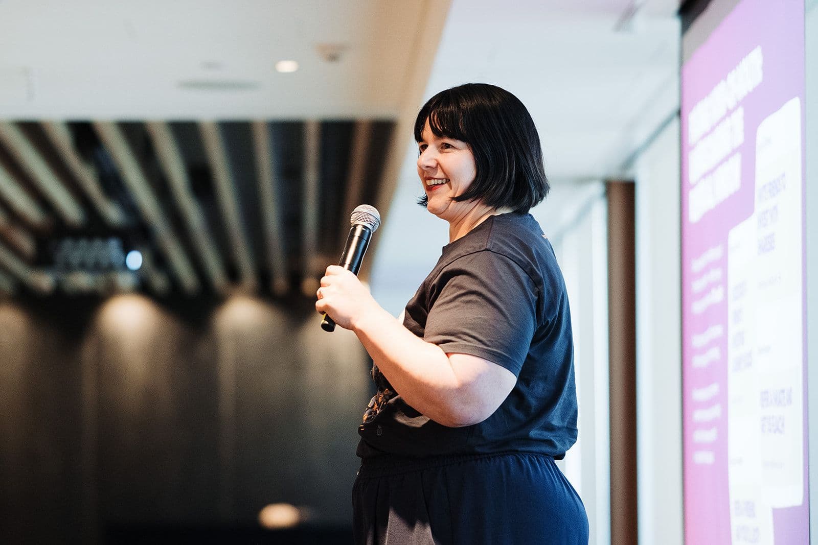 a woman is holding a microphone in front of a projector screen .