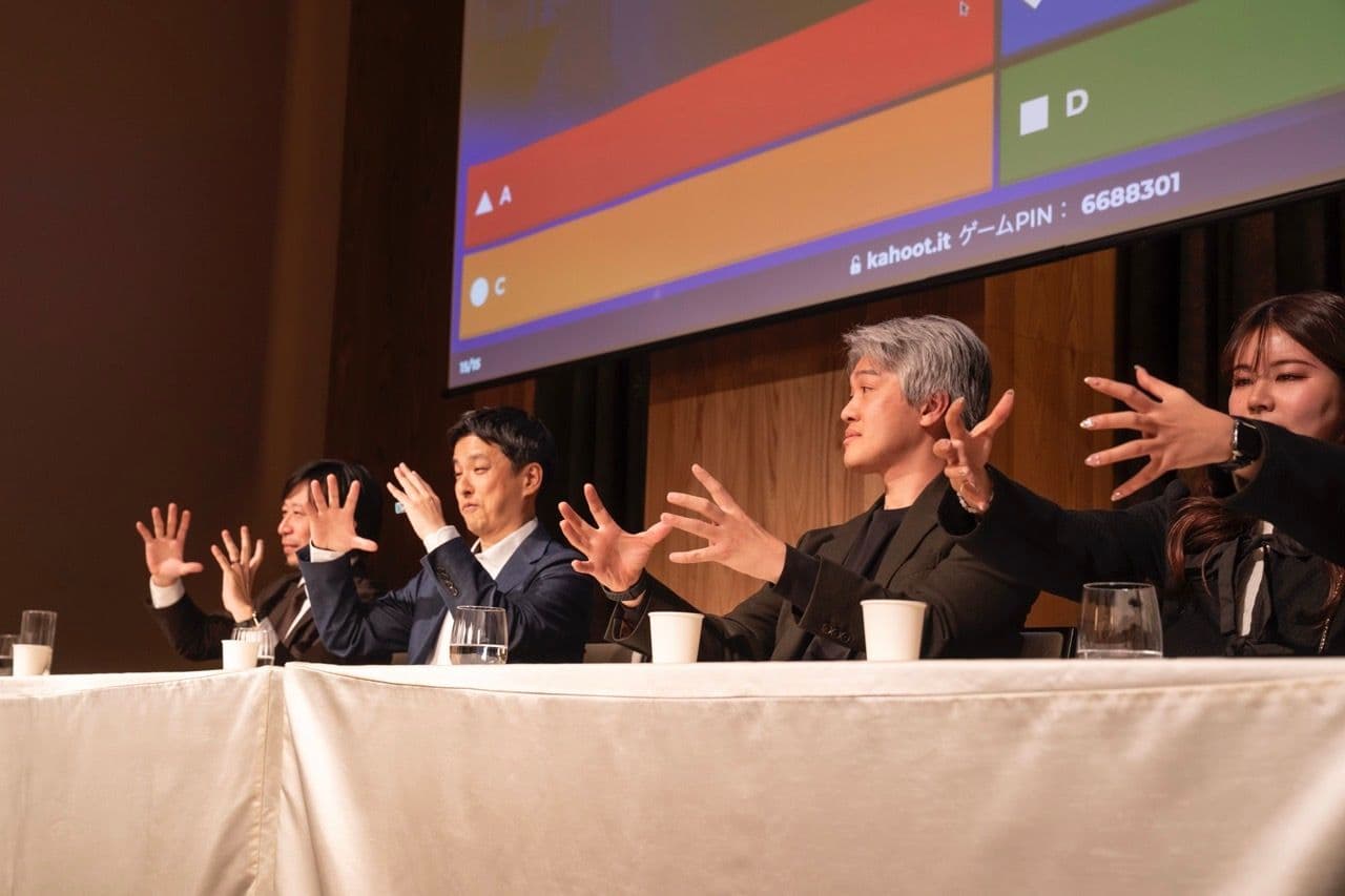 a group of people are sitting at a table with their hands in the air .