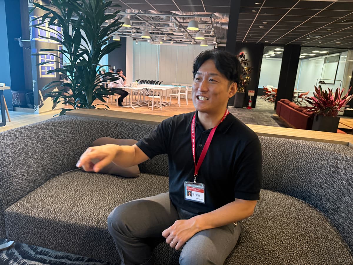 a man is sitting on a couch in an office and smiling .