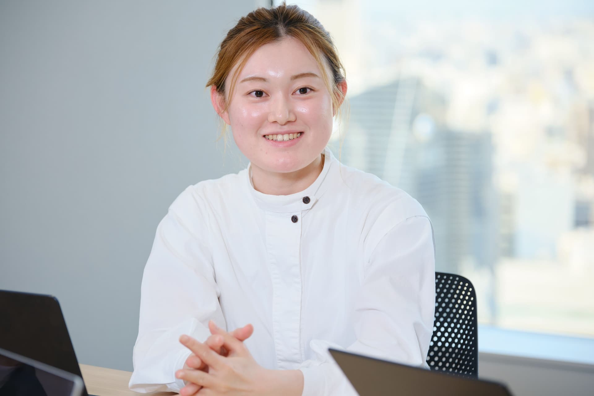 a woman is sitting at a table with a laptop and smiling .