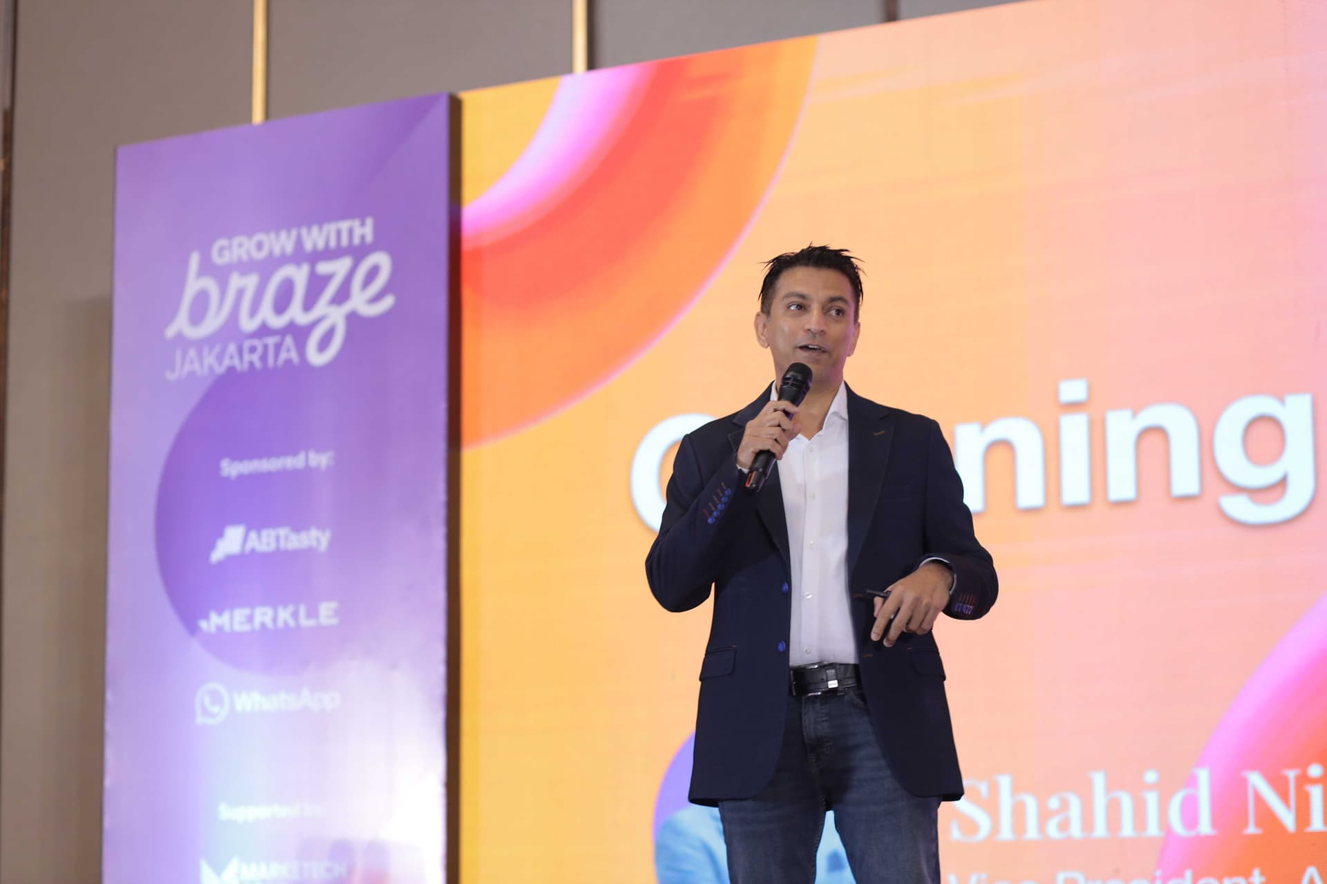 a man is standing on a stage holding a microphone and giving a speech .