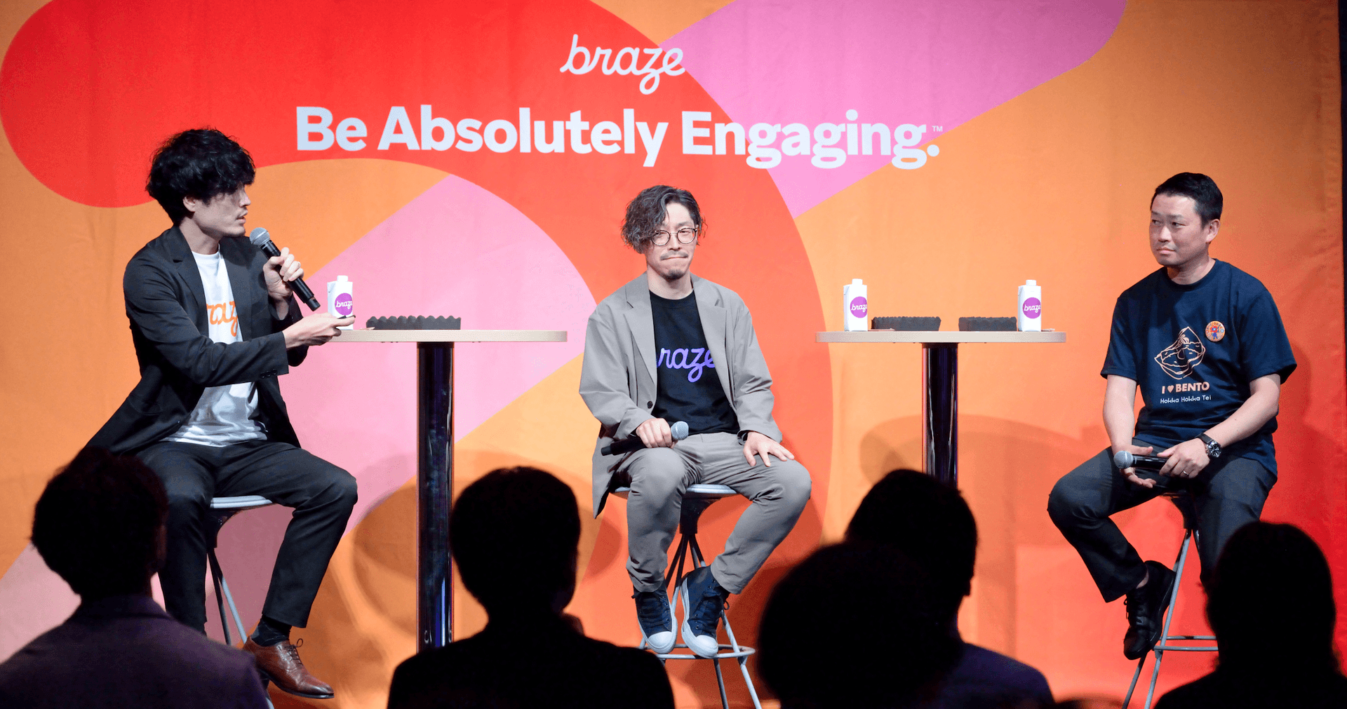 three men are sitting in front of a sign that says braze be absolutely engaging