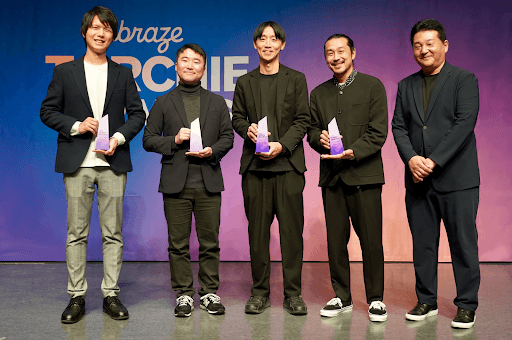 「トーチアワード」の背景幕を背に、ステージ上で輝く紫色の賞状を手に笑顔を見せる5人の男性。