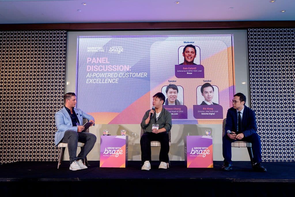 Panel discussion on AI-powered customer excellence with three speakers on stage in front of a large screen.