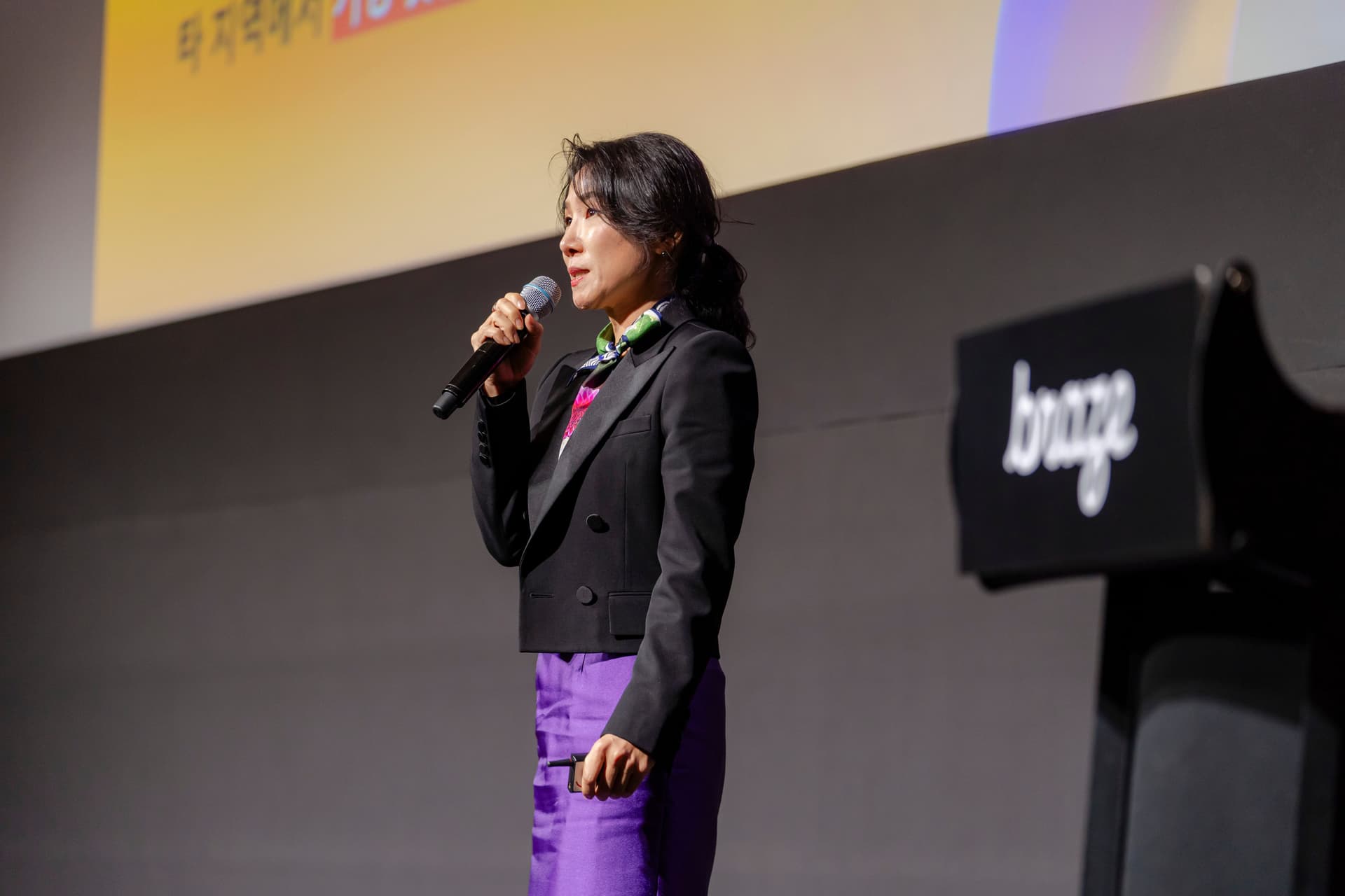 a woman is standing on a stage holding a microphone .