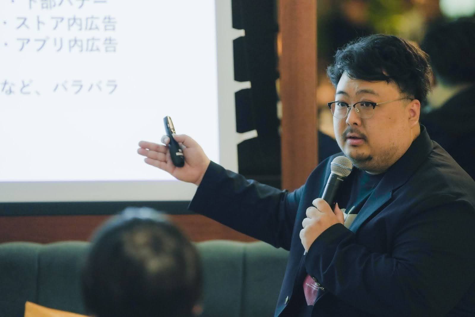 a man is holding a microphone and giving a presentation to a group of people .