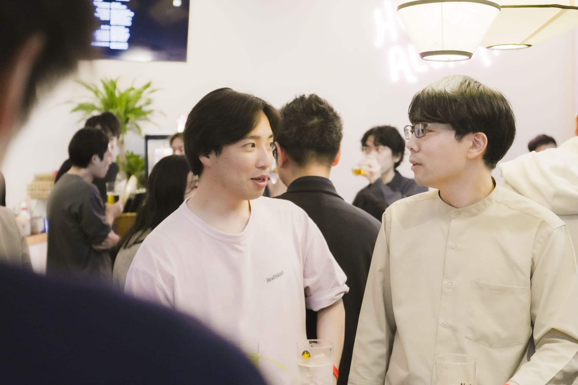 two men are standing next to each other in a crowded room talking to each other .