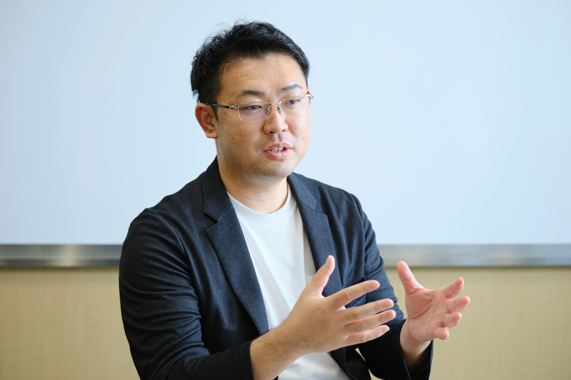 a man in a suit and glasses is talking with his hands outstretched .