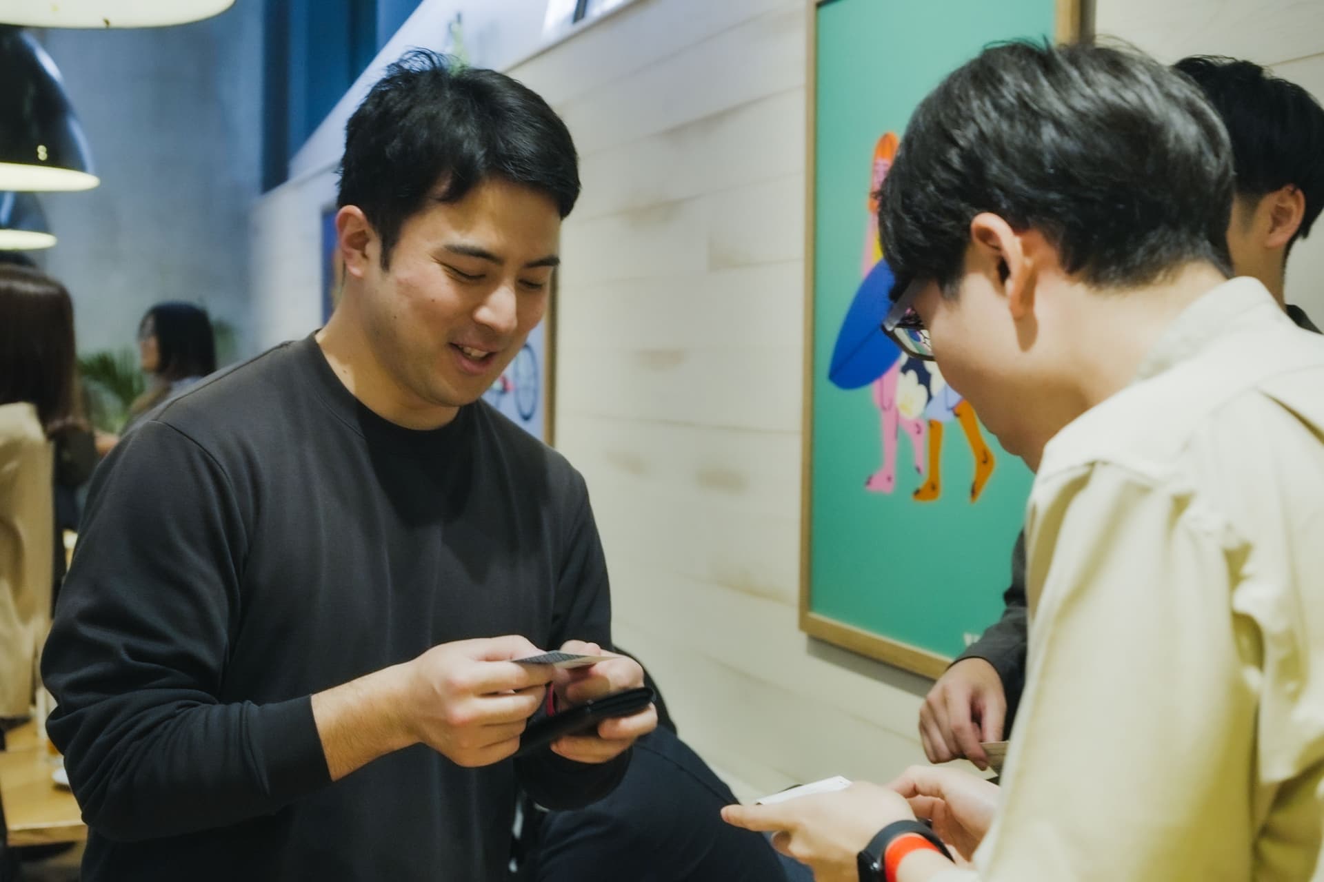 two men are looking at their phones in a room .