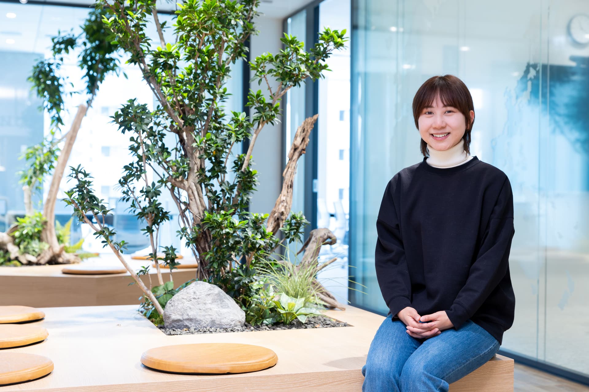 a woman is sitting on a bench in front of a tree .
