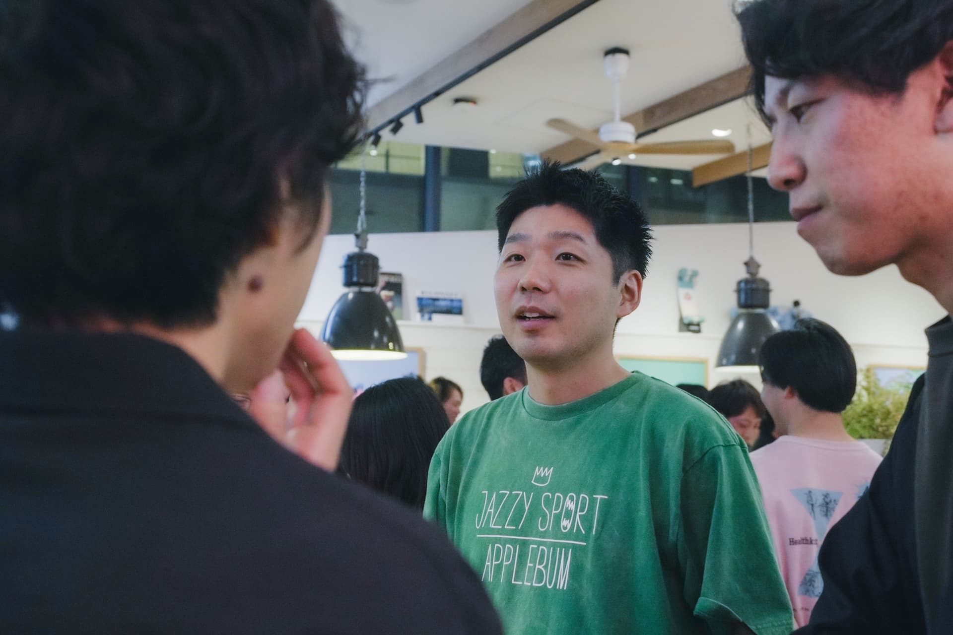a group of young men are standing in a room talking to each other .
