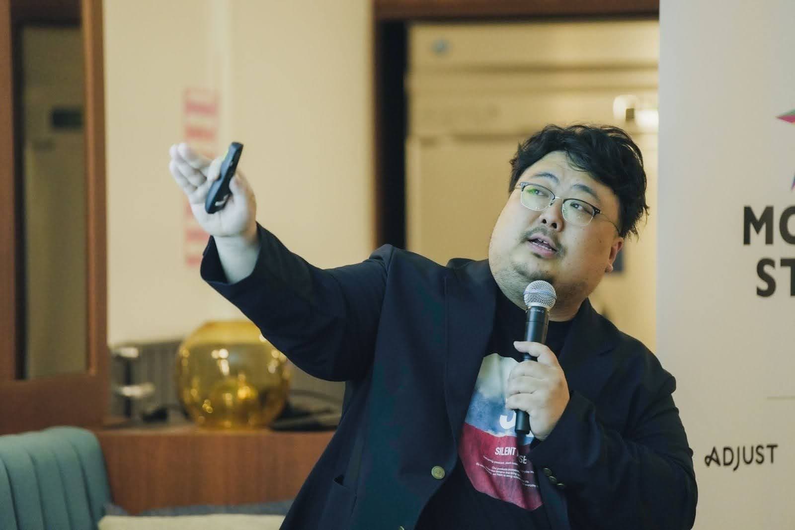 a man in a suit is holding a microphone and giving a presentation .