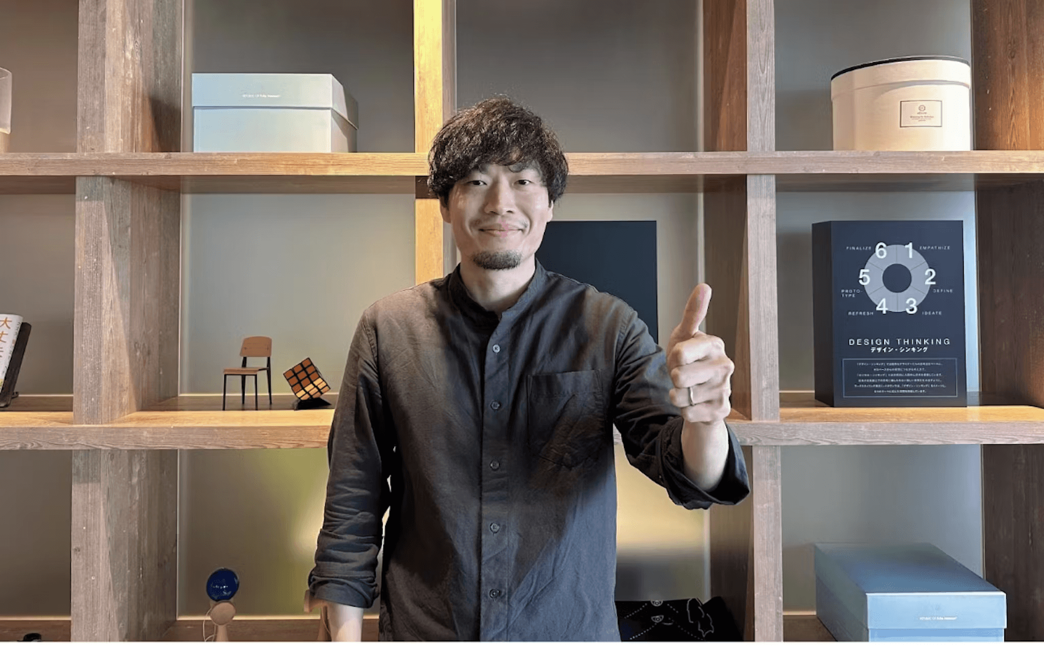 a man giving a thumbs up in front of a book titled design thinking