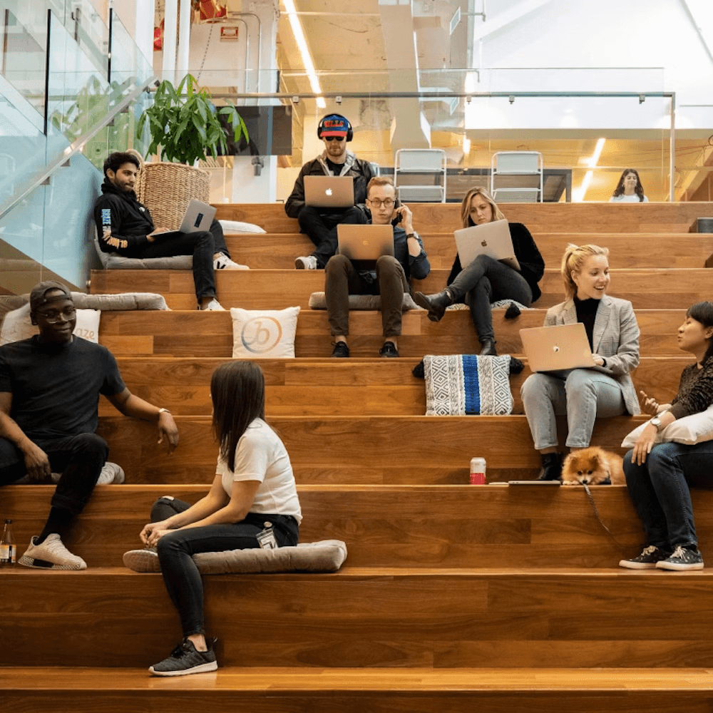 a group of people are sitting on a set of stairs using laptops
