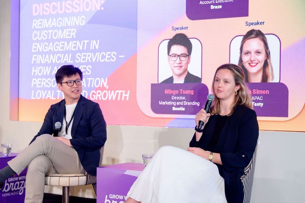 A man and a woman on stage during a panel discussion on financial services, with the woman speaking into a microphone.