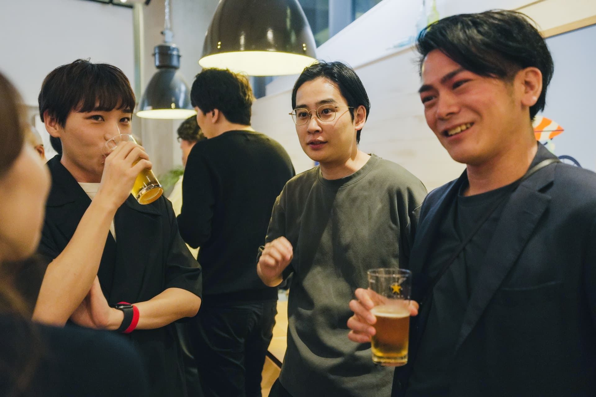 a group of people are standing around a table drinking beer .