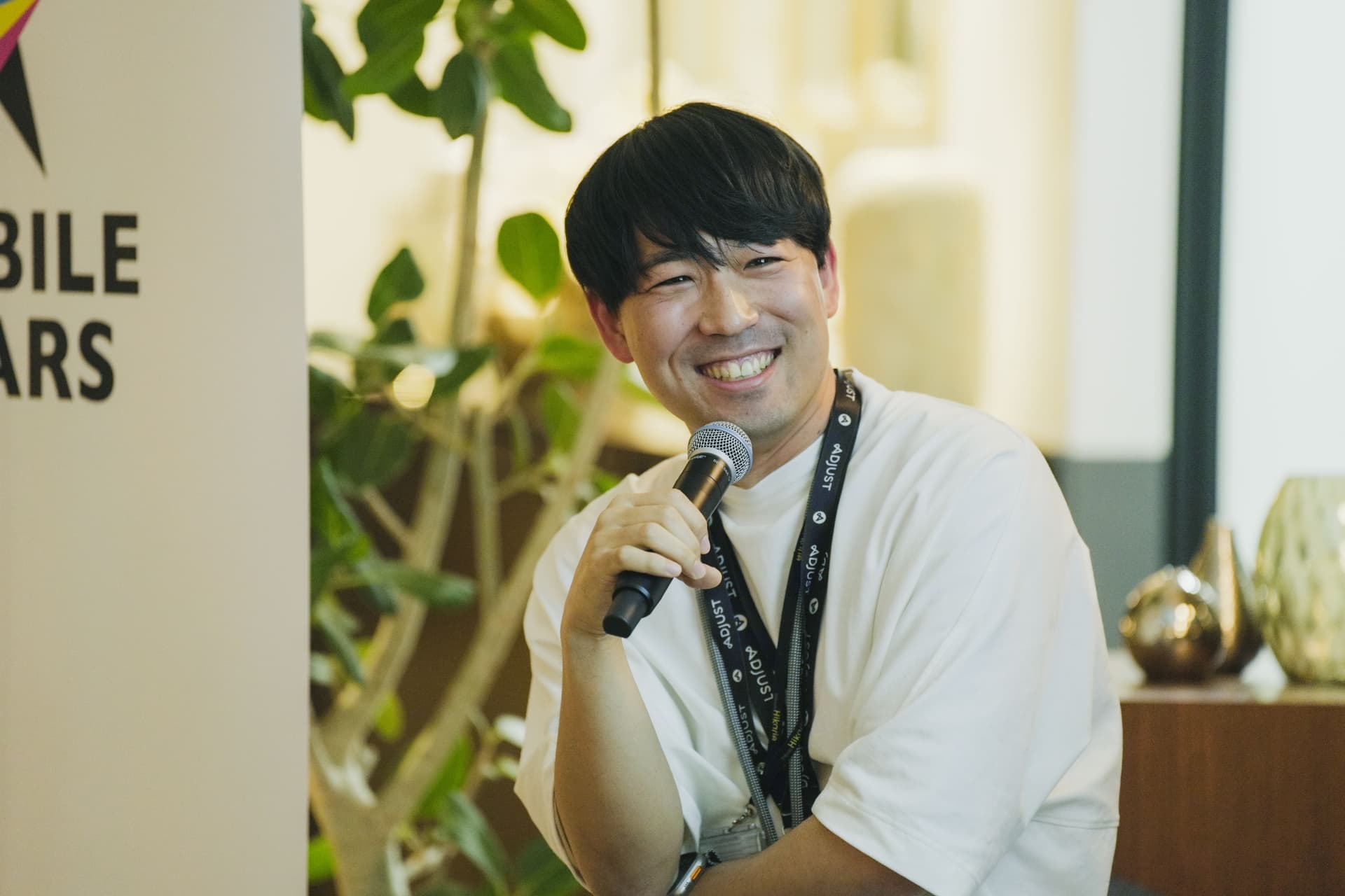 a man is sitting in front of a microphone and smiling .