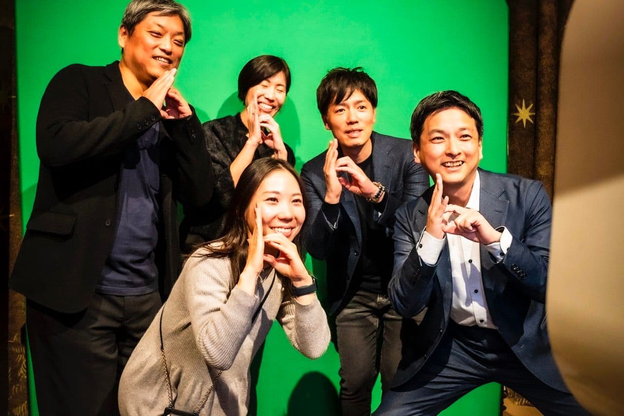 a group of people are posing for a picture in front of a green screen .
