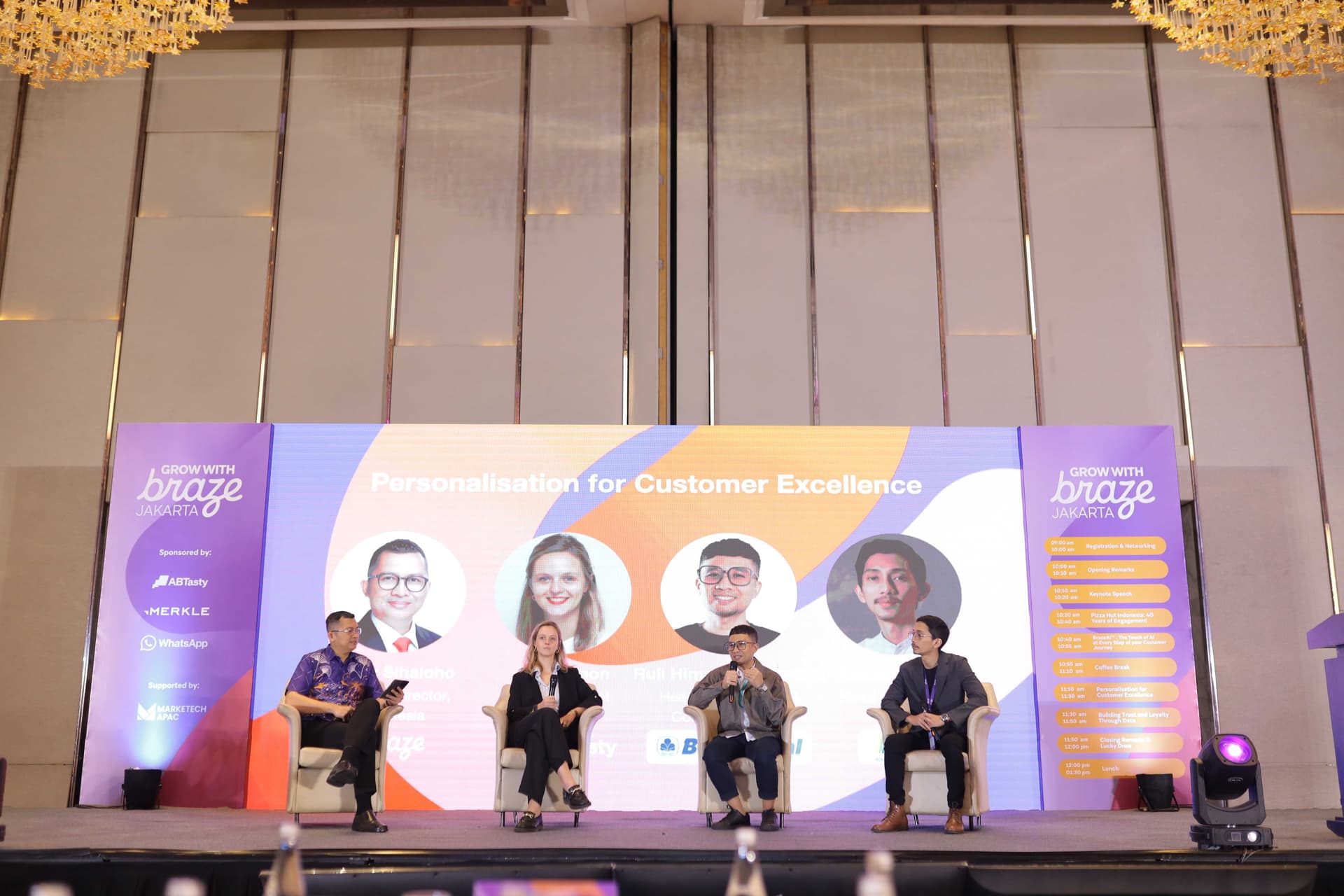 a group of people are sitting on a stage in front of a large screen .