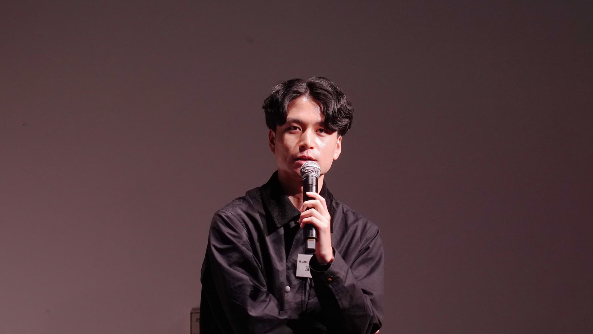 a young man is sitting in front of a microphone .