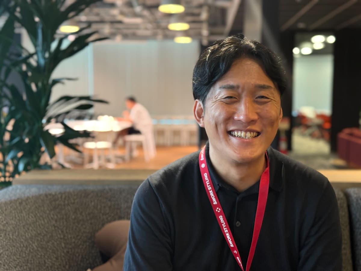 a man wearing a lanyard is smiling for the camera while sitting on a couch .