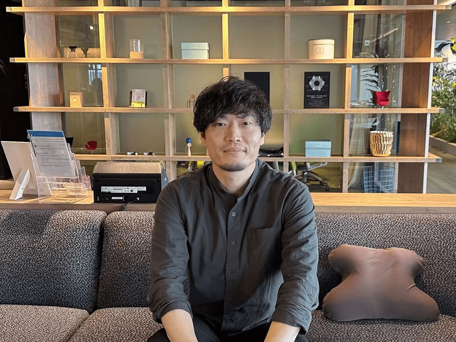 a man sits on a couch in front of a shelf with a sign that says ' a ' on it