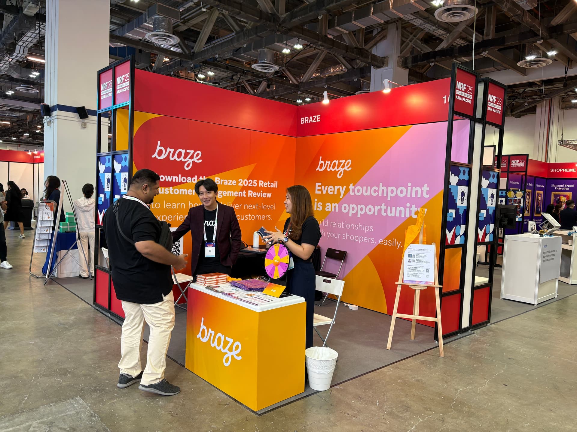 a group of people are standing around a booth at a convention .