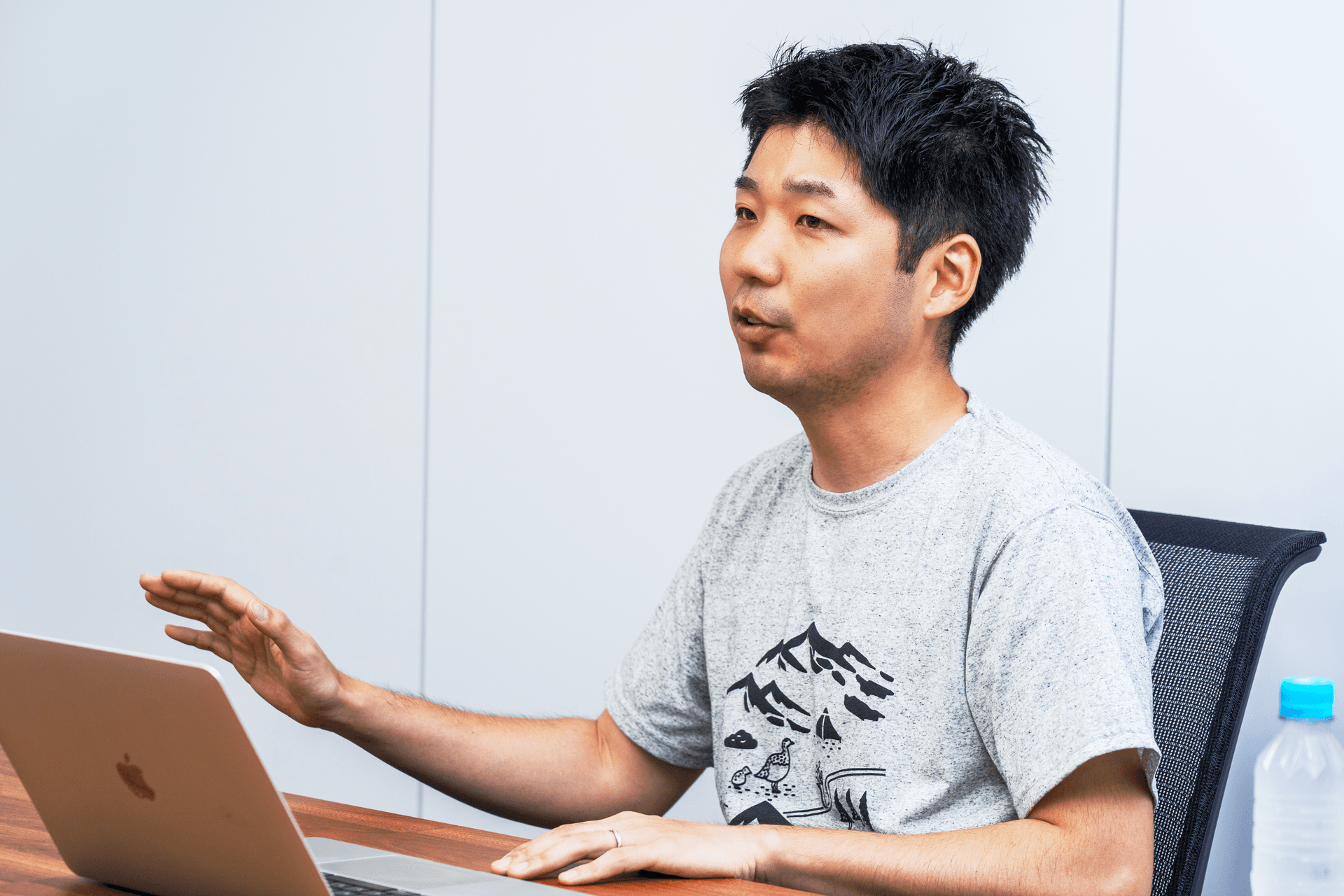 a man sitting at a desk with an apple laptop