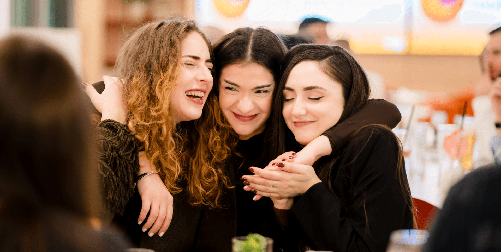 Three women embracing and laughing together.