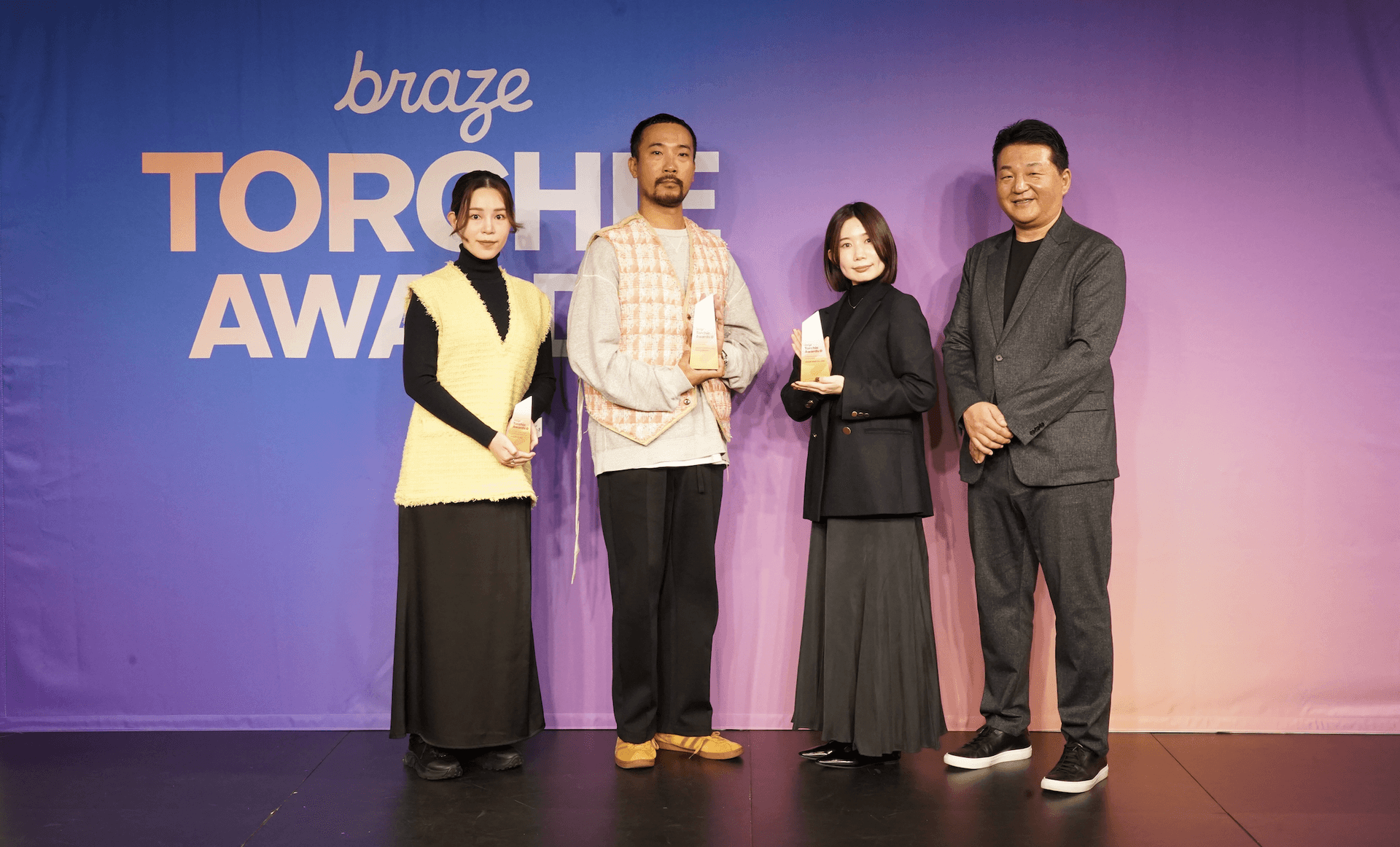 a group of people standing in front of a braze torch awards sign
