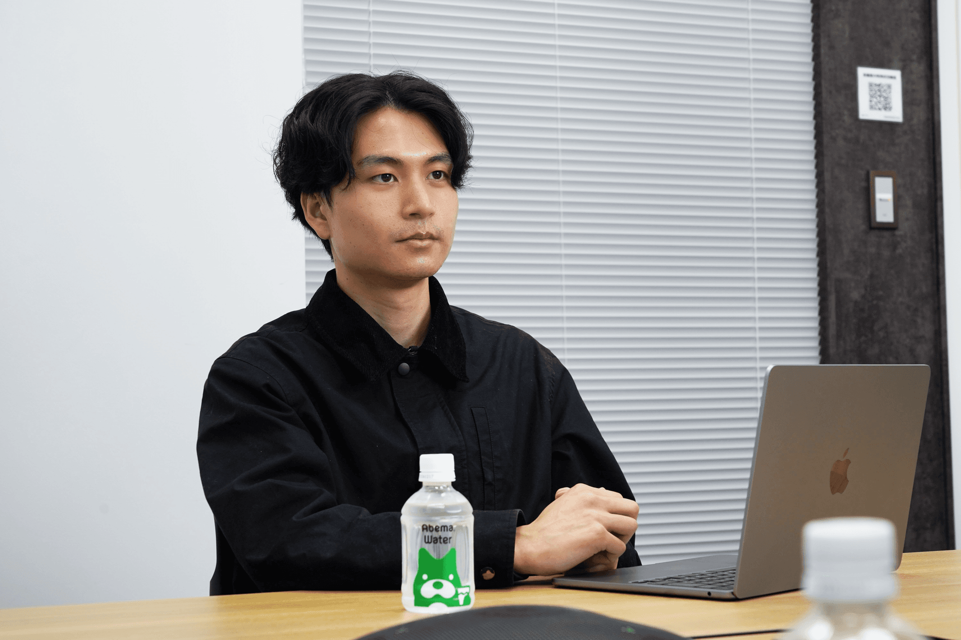 a man sits at a table with a laptop and a bottle of health drink