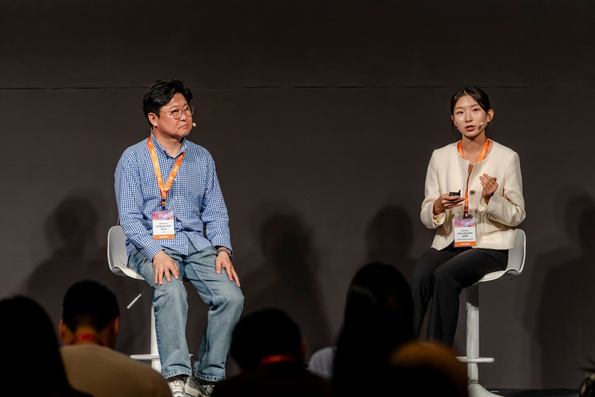 a man and a woman are sitting on stools in front of a crowd .