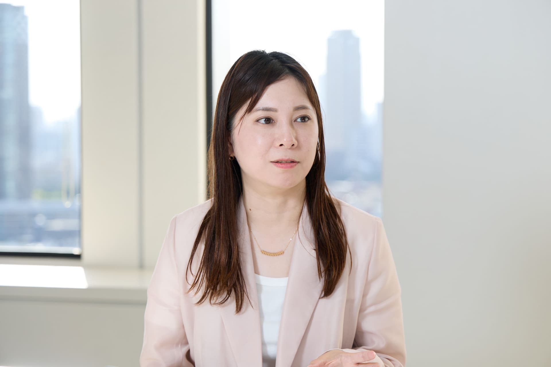 マーケティング部 リレーション推進グループ マネジャー 田中 空見子氏がインタビューに答える様子。ピンクのジャケットに白いシャツを着ている