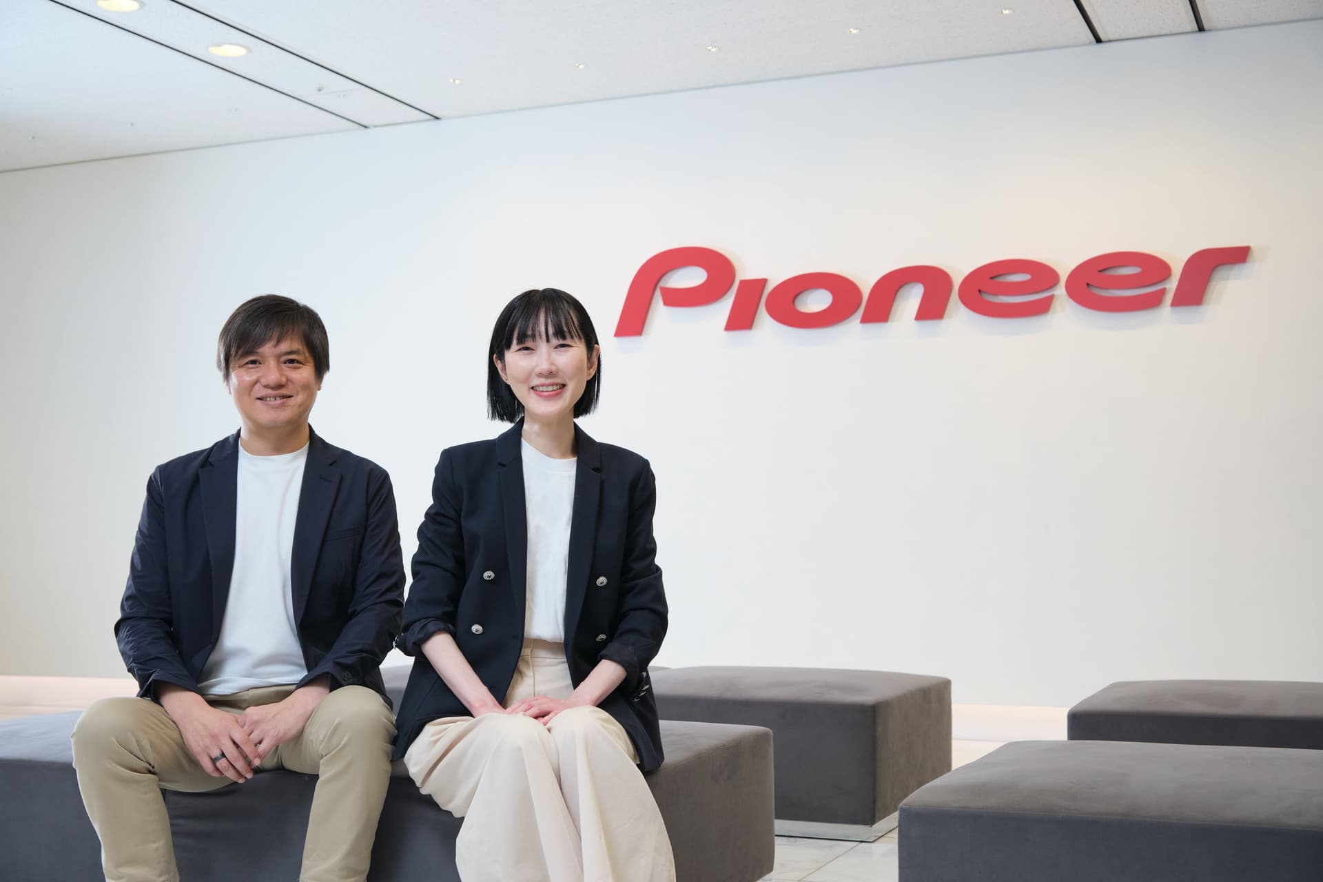 a man and a woman are sitting on a bench in front of a pioneer sign .