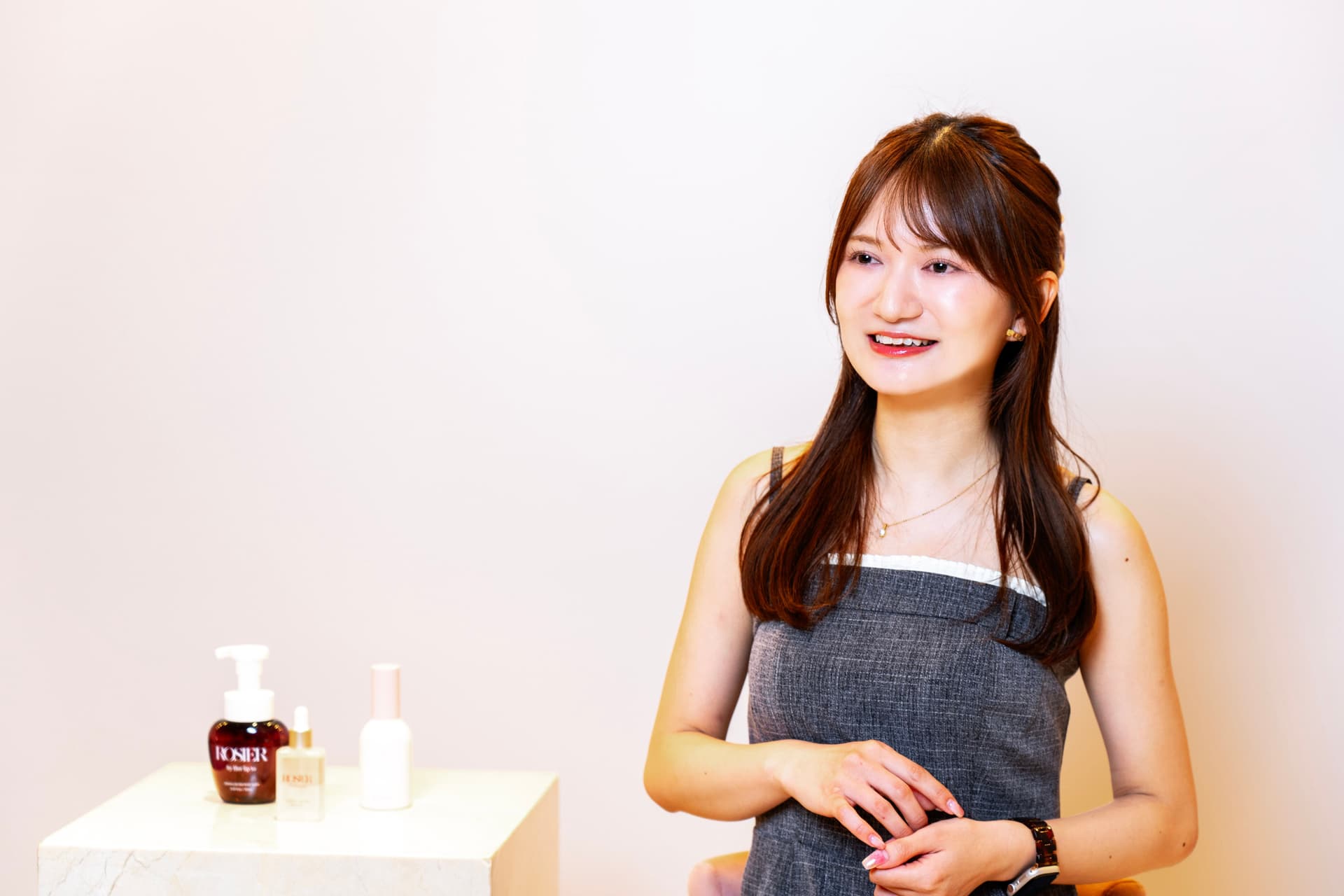 a woman is sitting in front of a table with bottles of cosmetics on it .