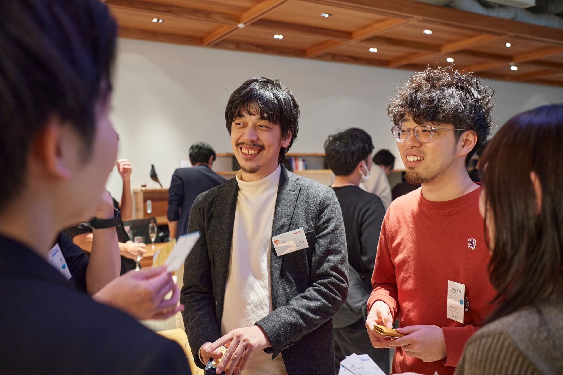 a group of people are standing in a room talking to each other .