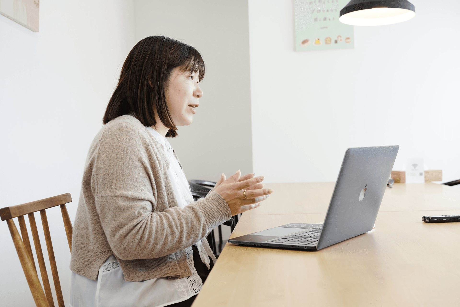 a woman sits at a table with an apple laptop