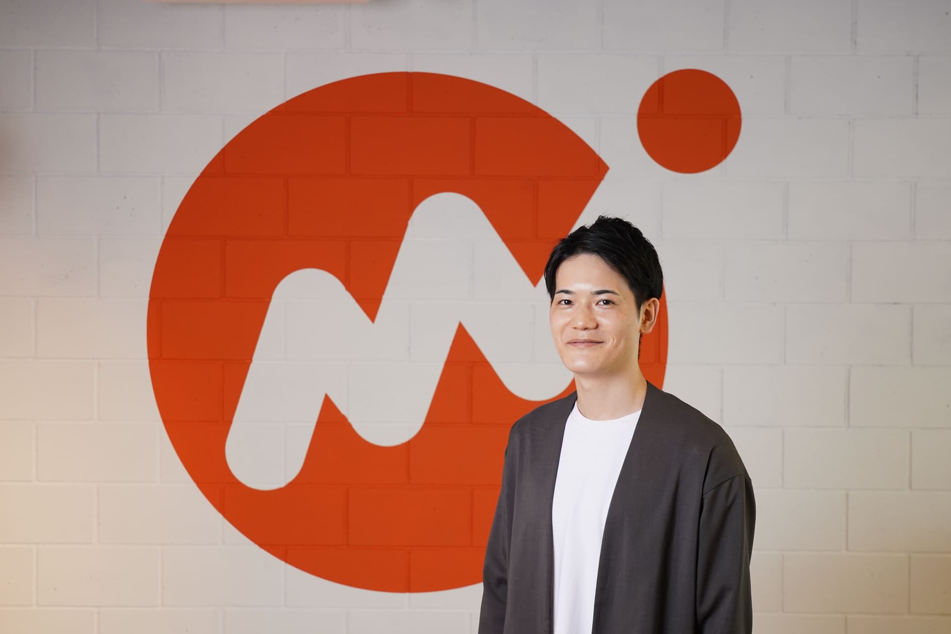 a man is standing in front of a large m on a brick wall .