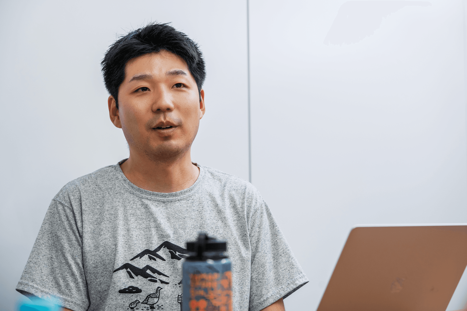 a man wearing a grey shirt with mountains on it
