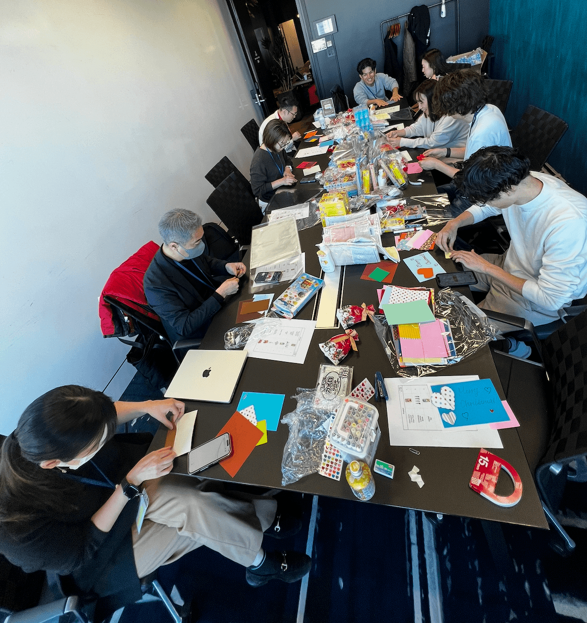 何人かの人がテーブルを囲み、色とりどりの紙や材料を使って工作活動に没頭している。