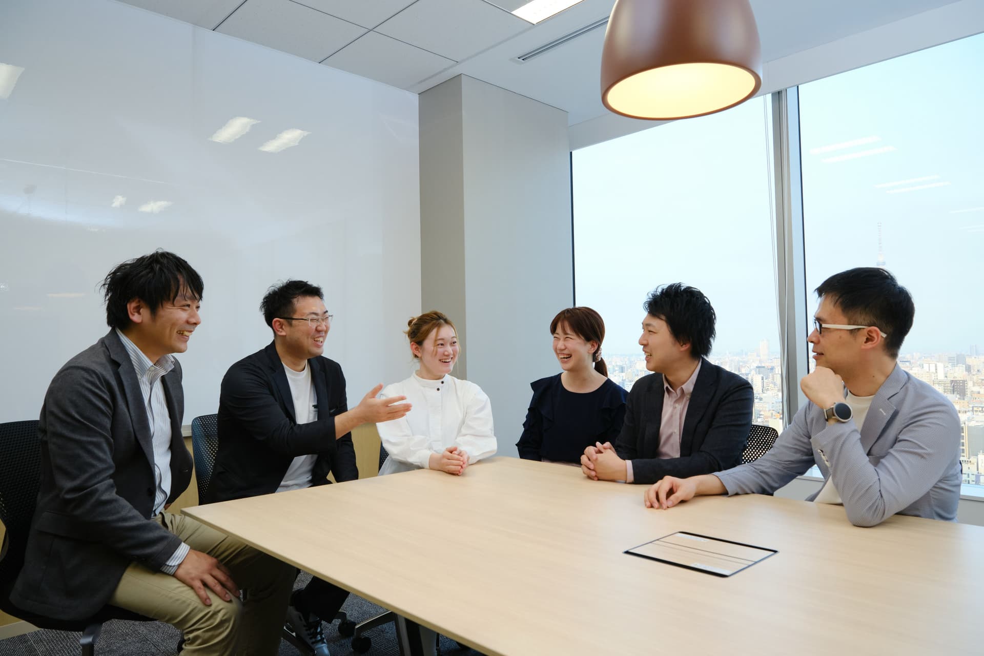 a group of people are sitting around a table in a conference room .
